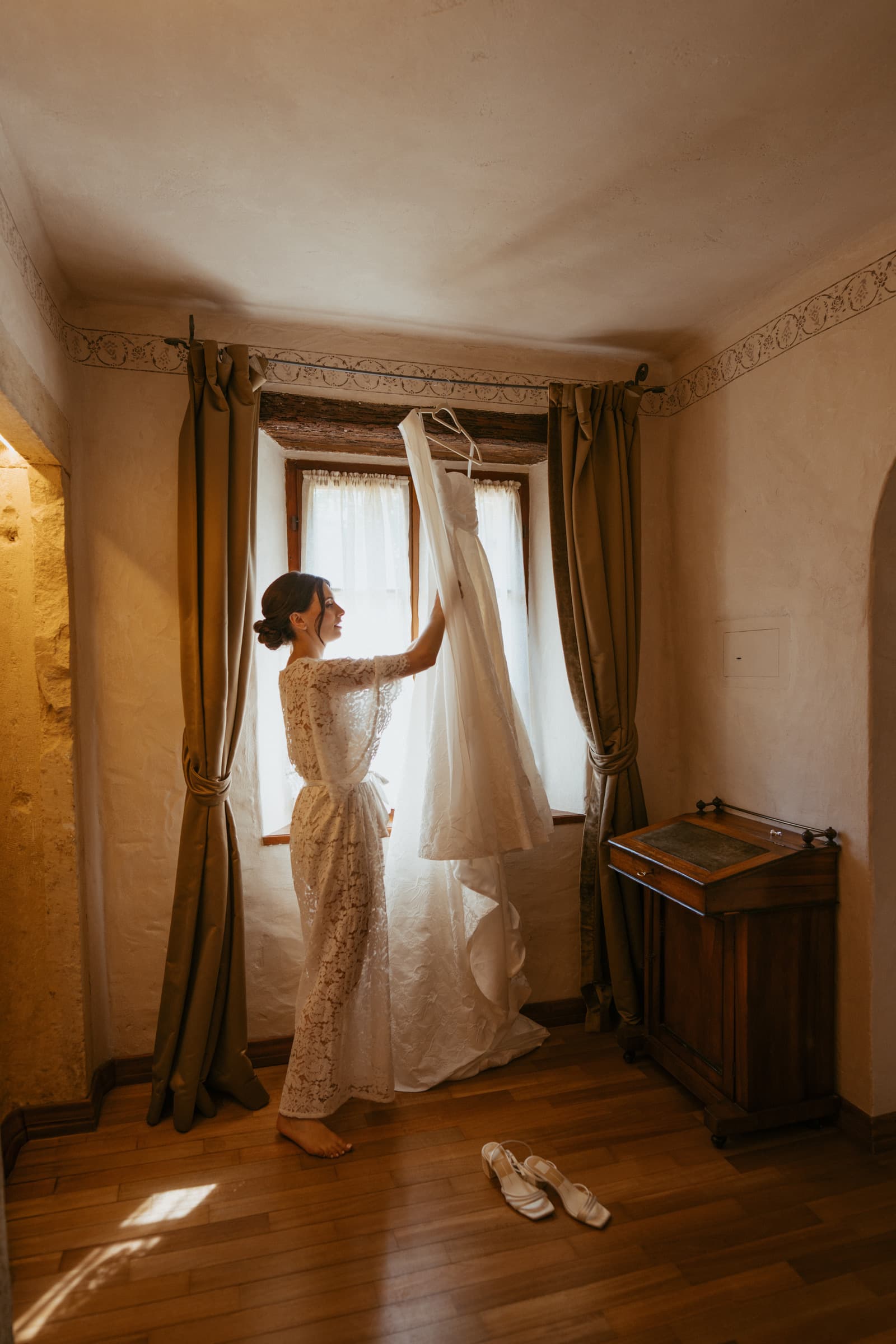 Bride with her wedding dress by a window, Italy