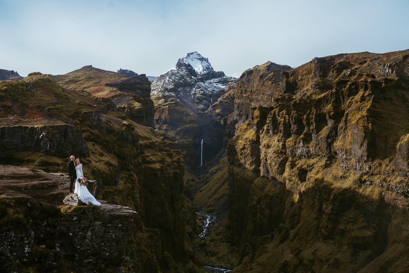 A couple in wedding attire who is eloping in iceland, standing in front of a canyon in iceland