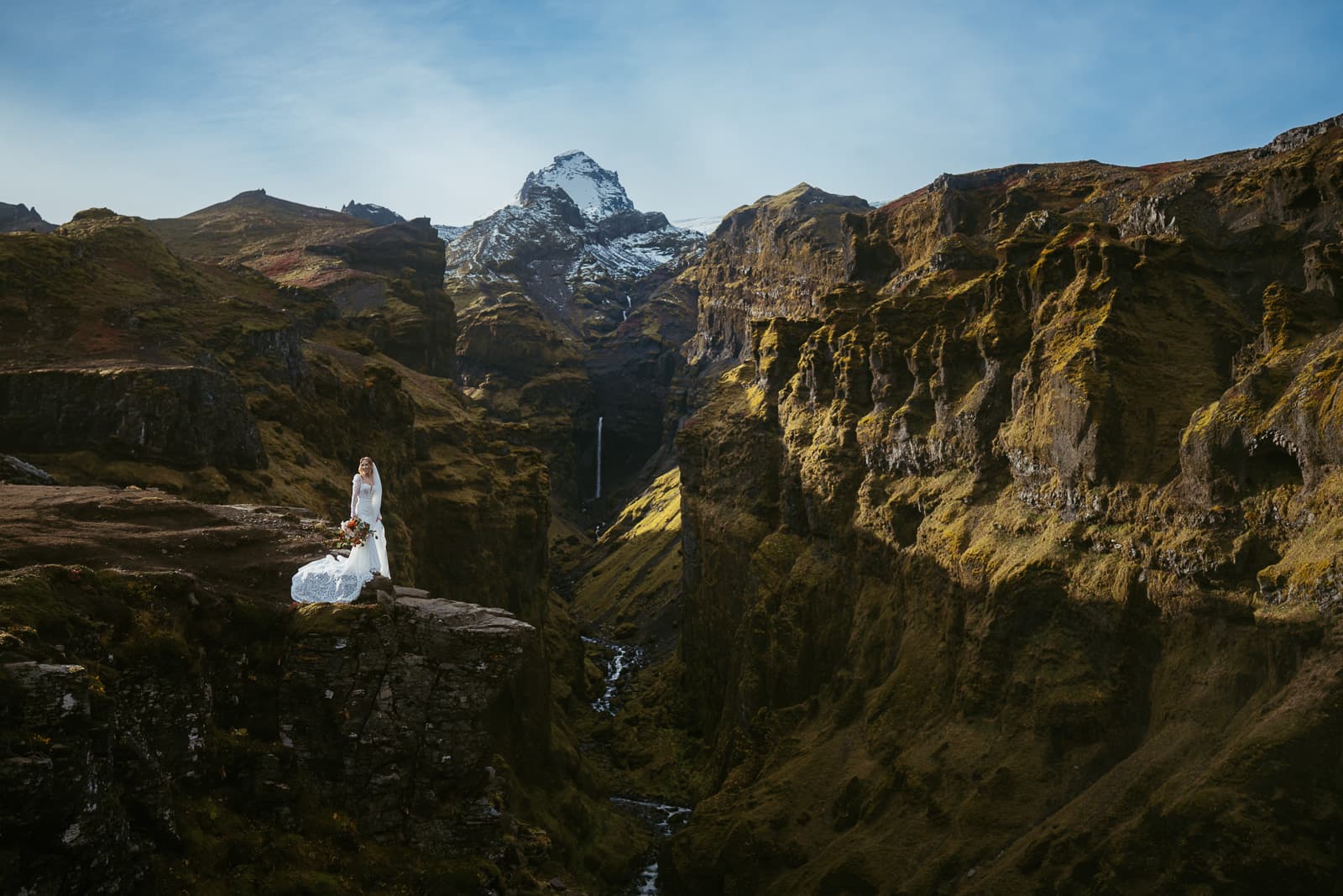 A couple eloping in Iceland, just the two of them standing on a rock with majestic green background