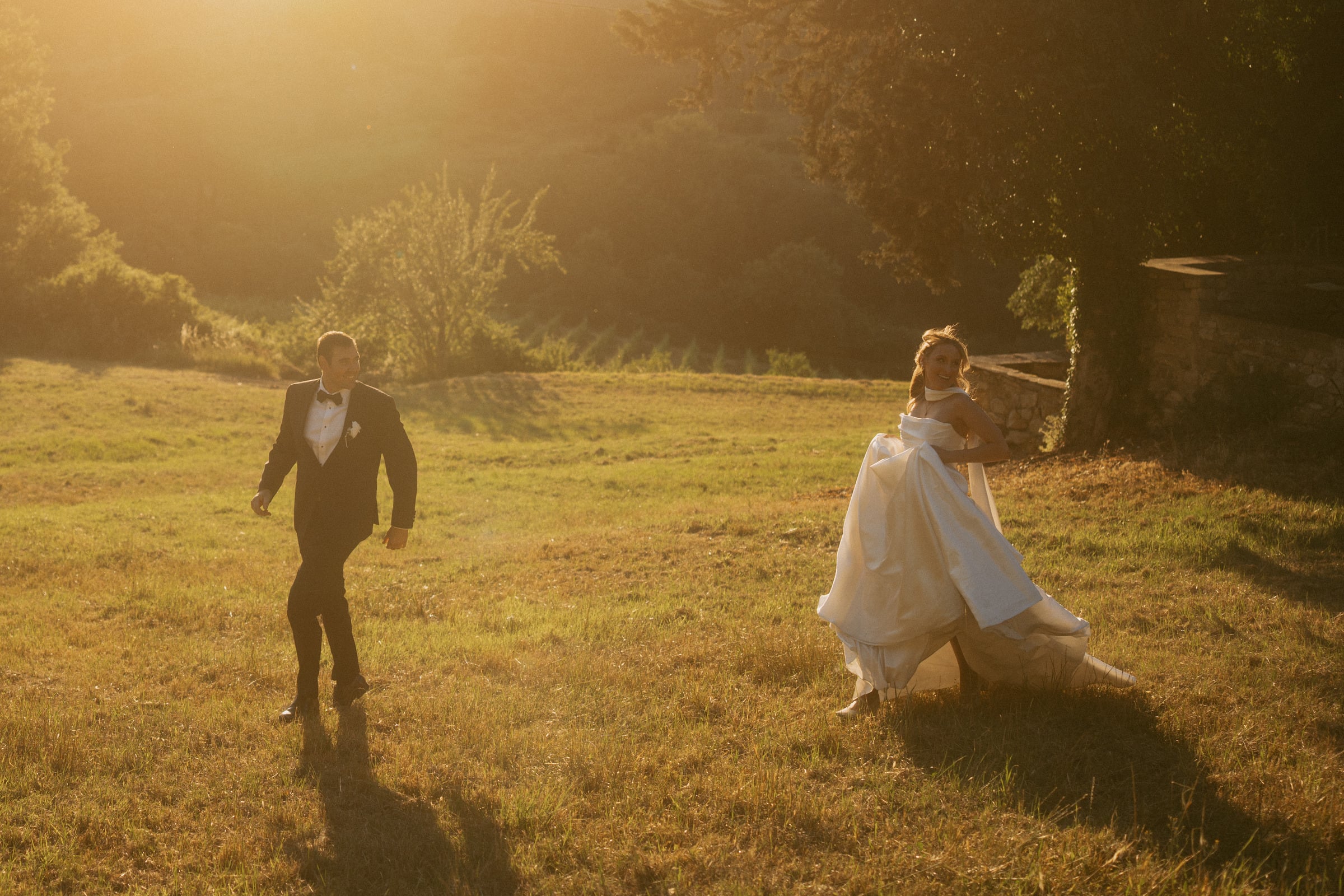 Bride and groom running through a field at golden hour in Italy