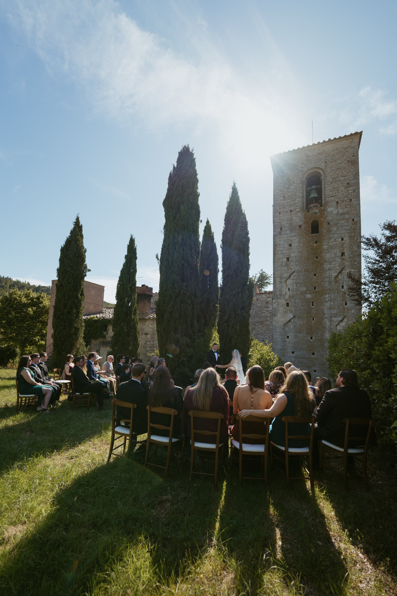 Wedding ceremony beneath a bell tower and cypress trees in Tuscany, Italy