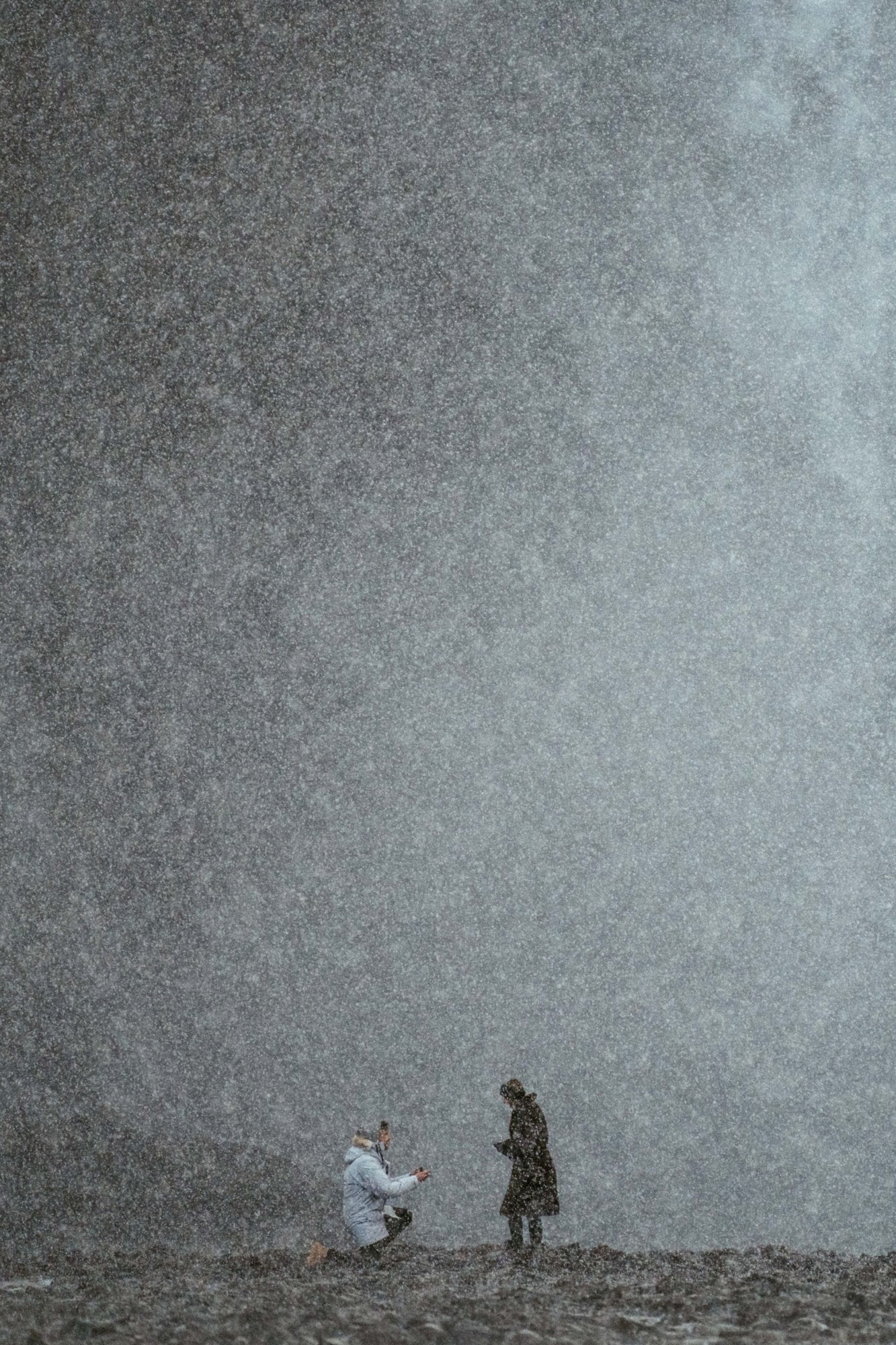 Proposal in a hailstorm in front of an Icelandic waterfall