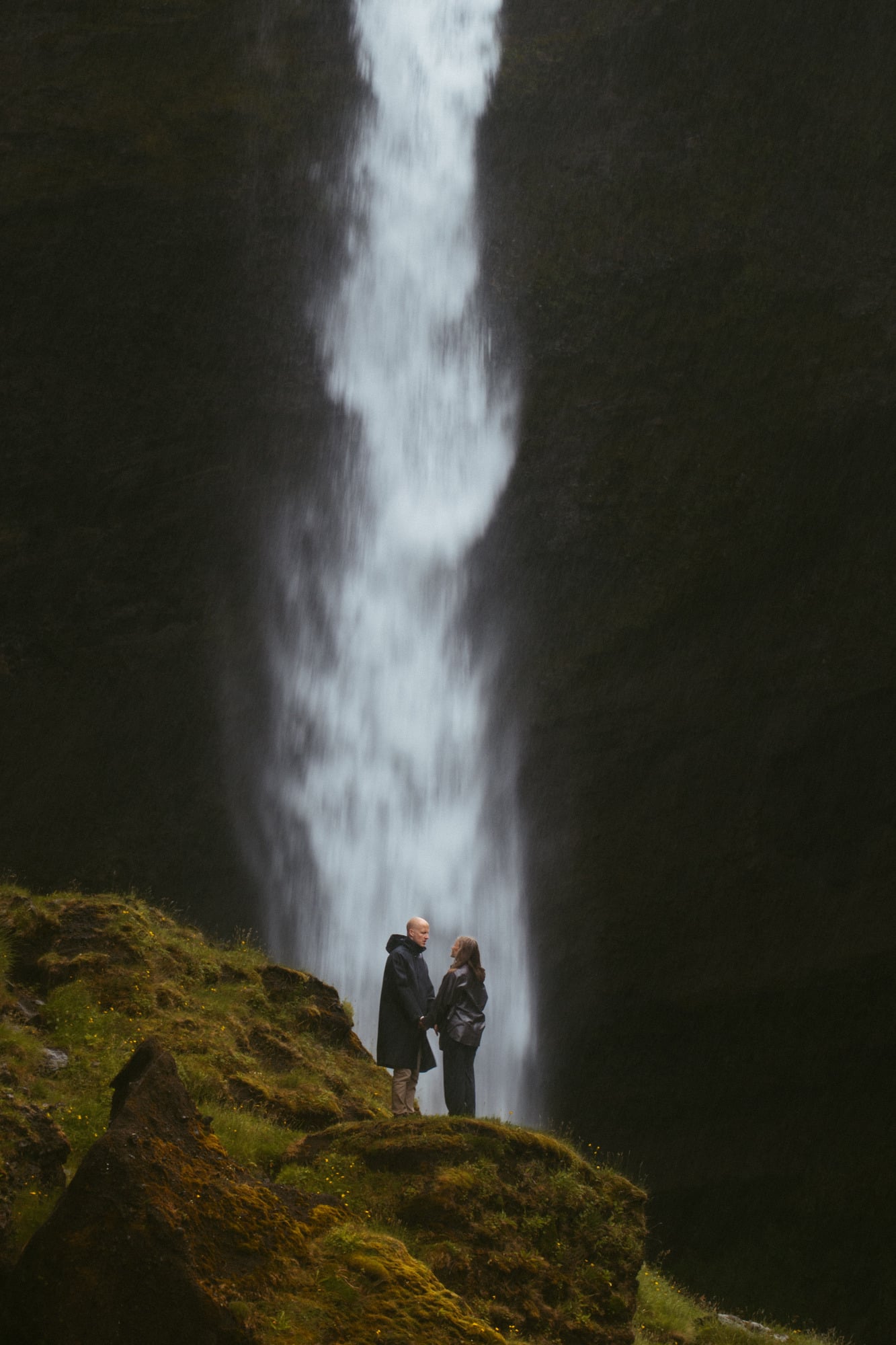 Couple beneath a towering Icelandic waterfall