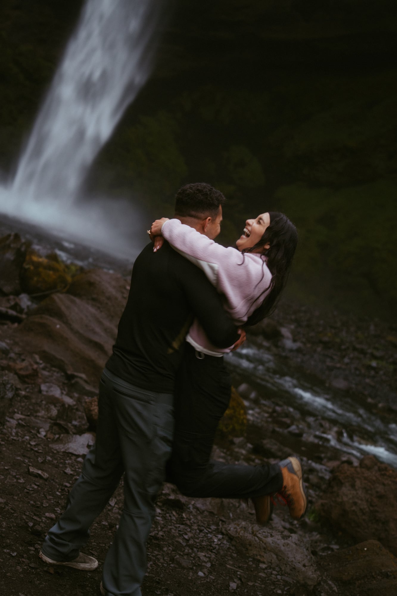 Couple spinning and laughing beside an Icelandic waterfall