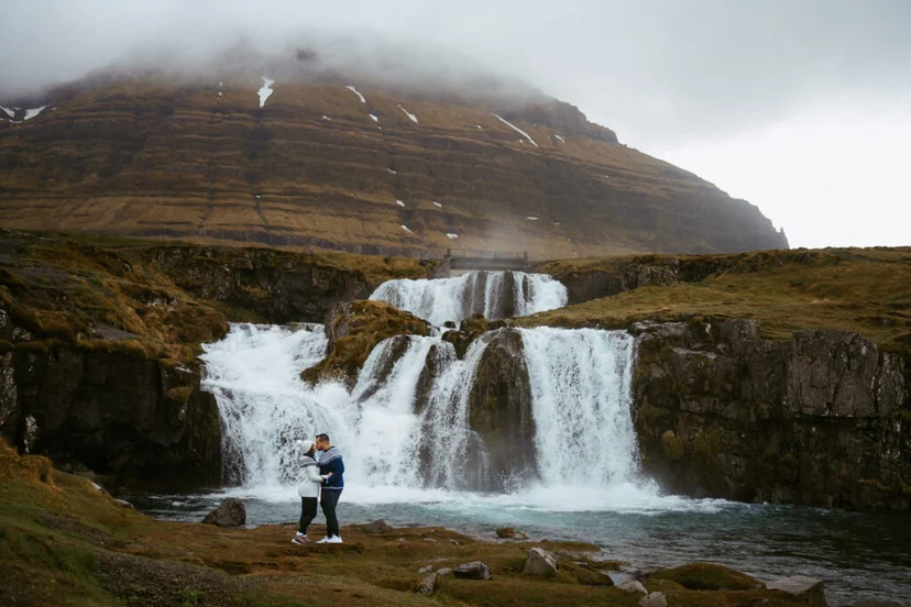 Couple standing before kirkjufellsfoss before getting engaged, misty day