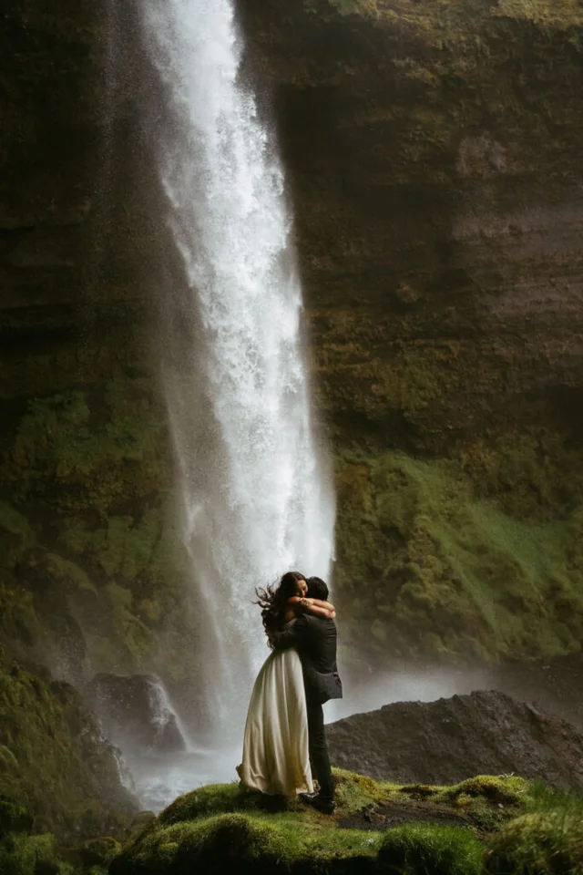 ouple hugging in front of Kvernufoss waterfall during an intimate Iceland elopement