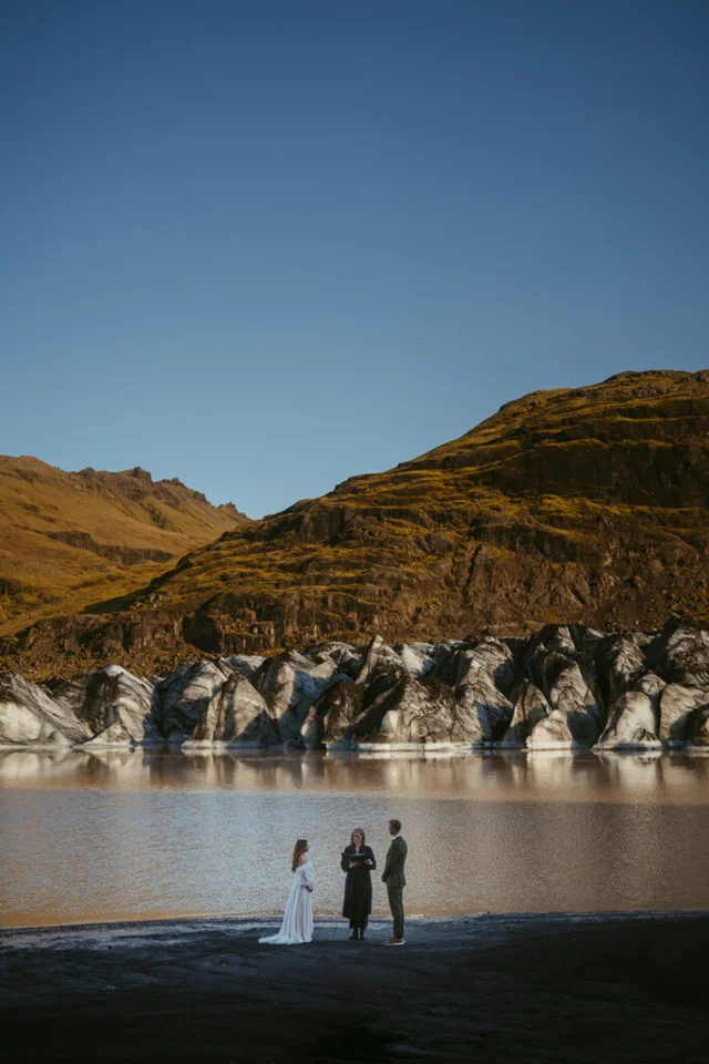 Couple eloping by the edge of Sólheimajökull glacier lagoon with mountains in the background