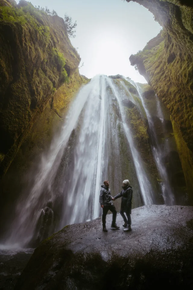 Couple standing on a rock inside the mossy canyon at Gljúfrabúi waterfall in South Iceland