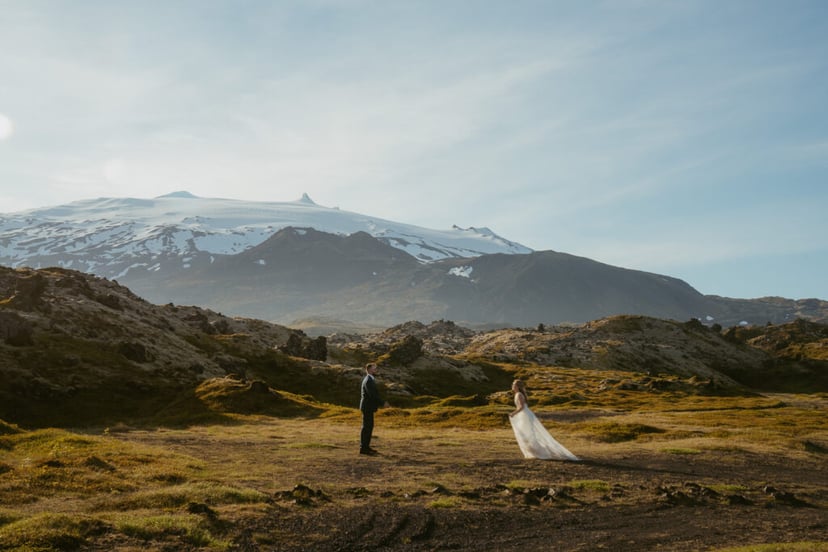 Bride and groom standing near lava fields and Snæfellsjökull glacier