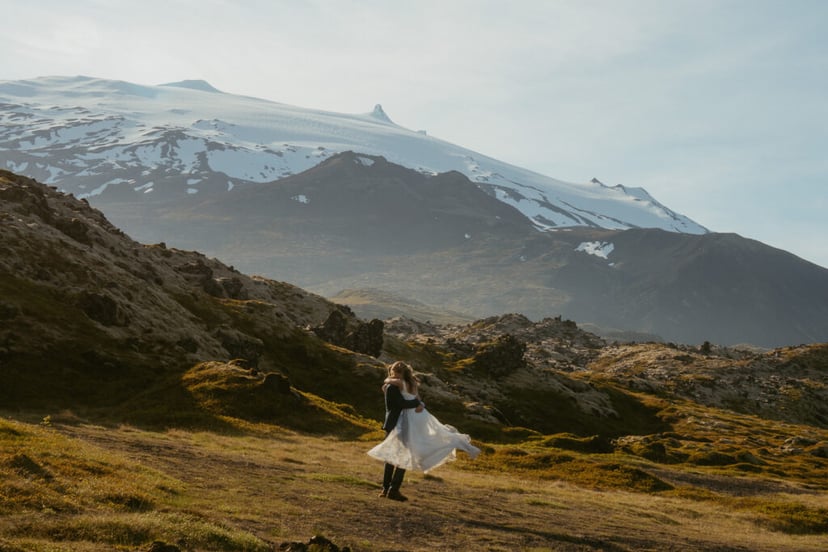 Bride and groom standing near lava fields and Snæfellsjökull glacier