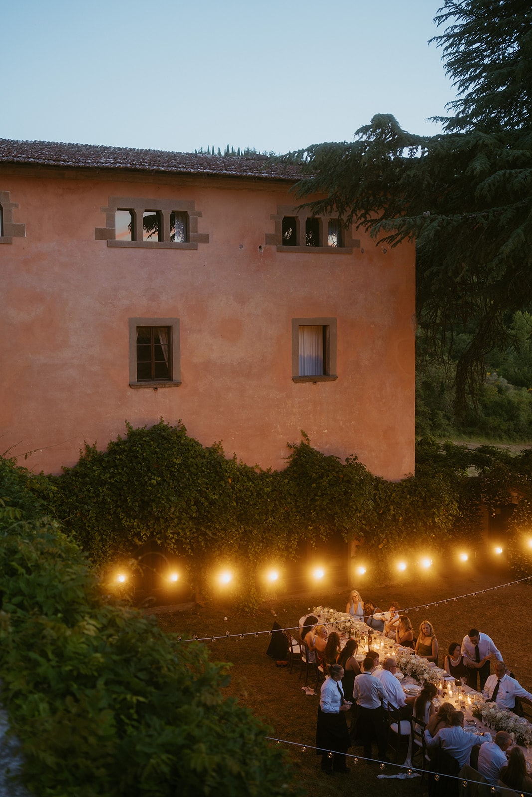 Long outdoor wedding dinner under string lights in Tuscany, Italy