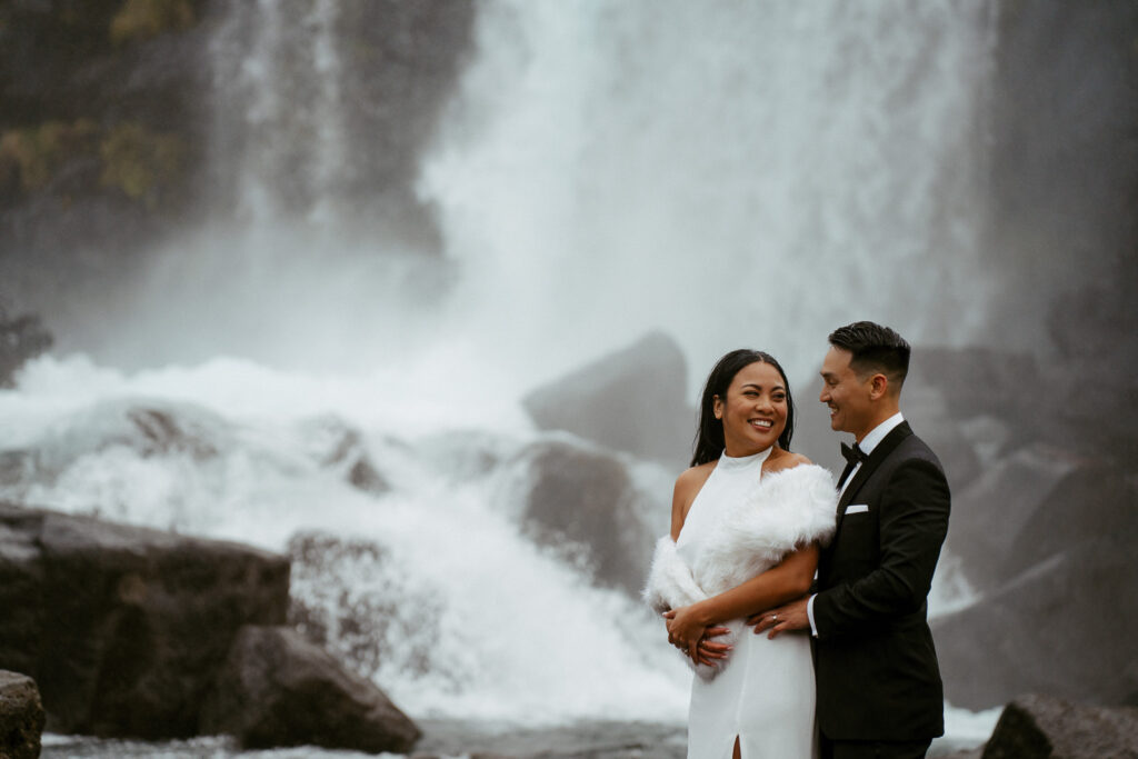 Wedding photos in oxararfoss, iceland, couple standing in front of a waterfall