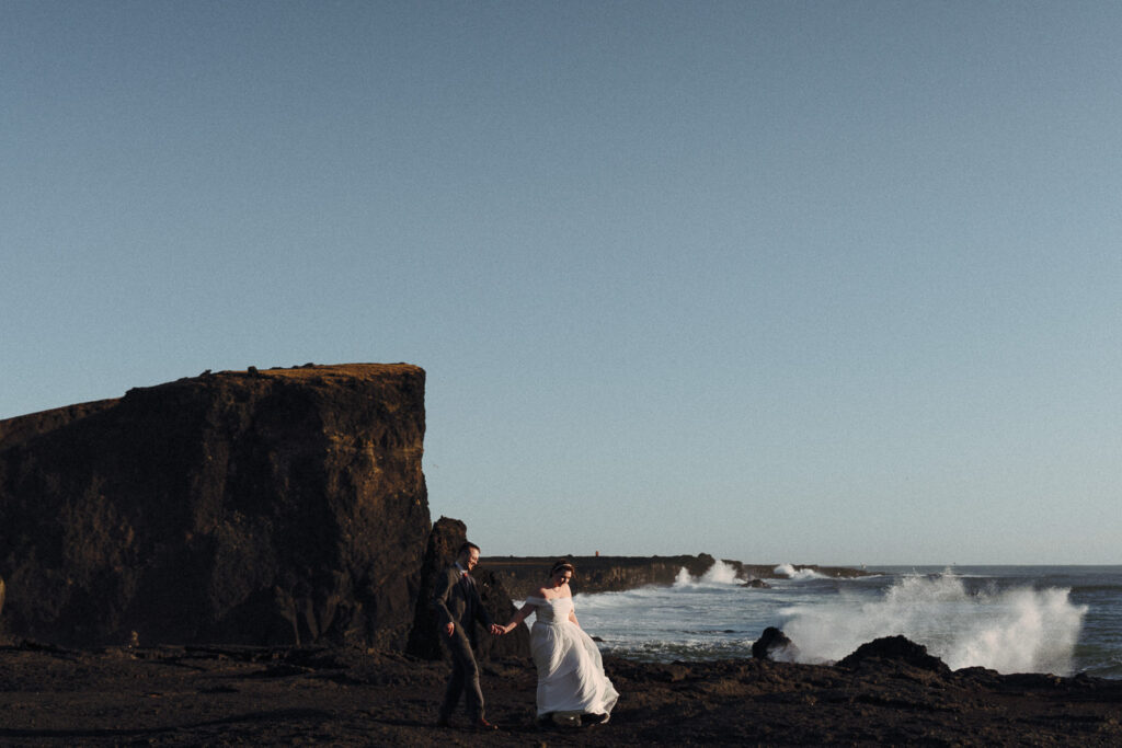 Reykjanesviti wedding photos in Iceland, couple walking when waves hit in the background