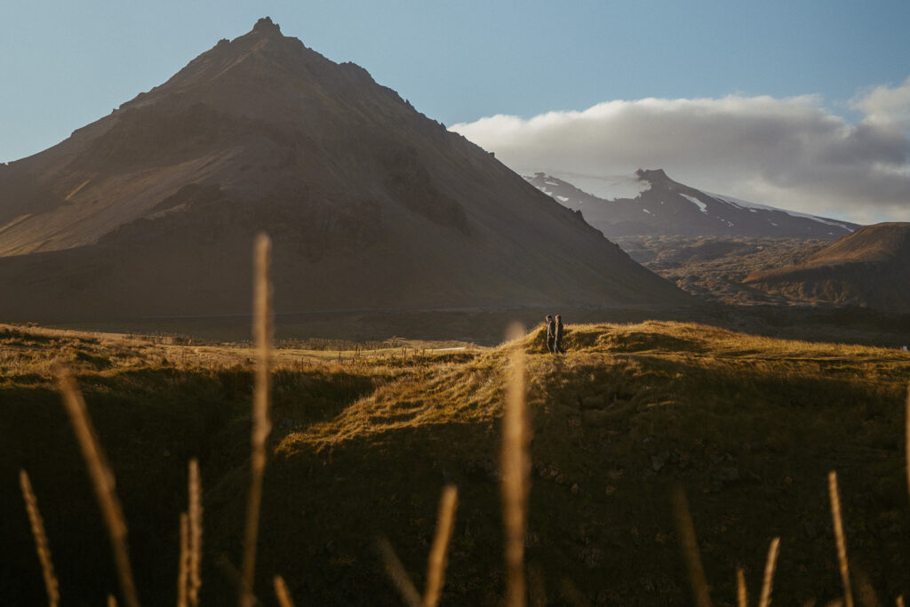 Couple exploring the rocky coastline of Arnarstapi during their anniversary photo session on the Snæfellsnes Peninsula in Iceland.
