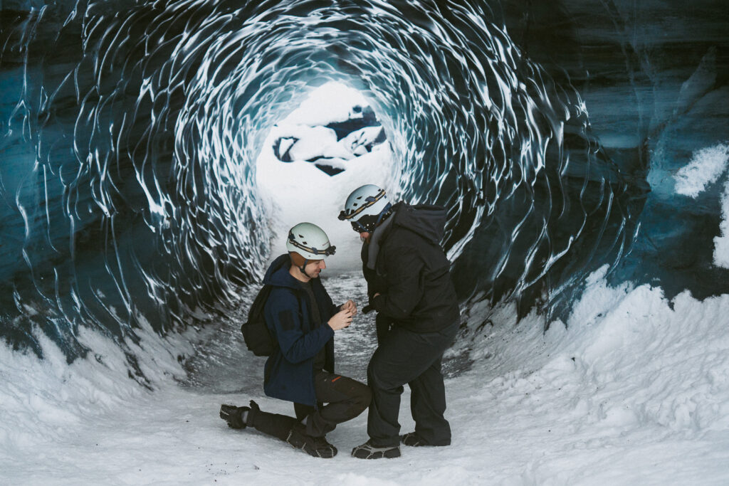 Man proposing inside icy blue Katla Ice Cave during a winter trip in Iceland