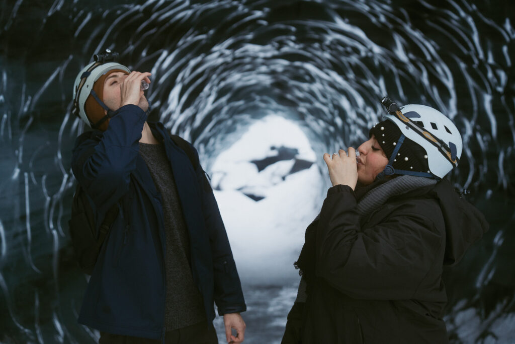 couple in ice cave taking a shot after getting engaged