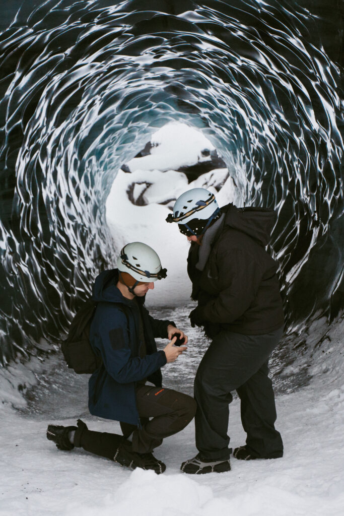 Man proposing inside icy blue Katla Ice Cave during a winter trip in Iceland