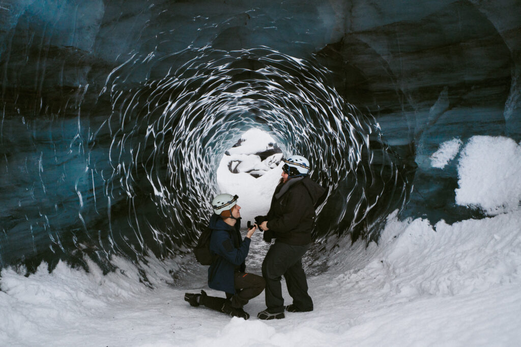 Man proposing inside icy blue Katla Ice Cave during a winter trip in Iceland