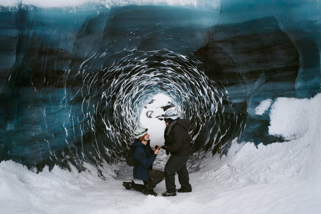 Man proposing inside icy blue Katla Ice Cave during a winter trip in Iceland