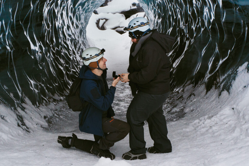 Man proposing inside icy blue Katla Ice Cave during a winter trip in Iceland