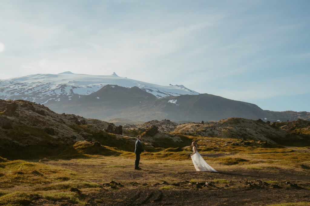 Bride and groom standing near lava fields and Snæfellsjökull glacier