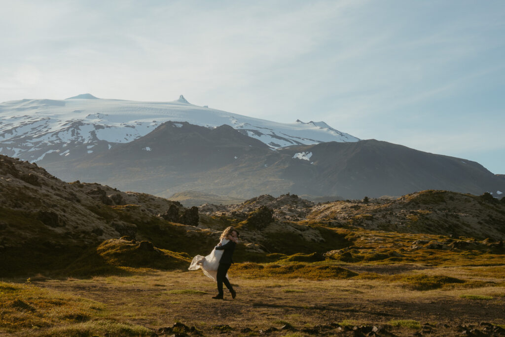 Bride and groom standing near lava fields and Snæfellsjökull glacier
