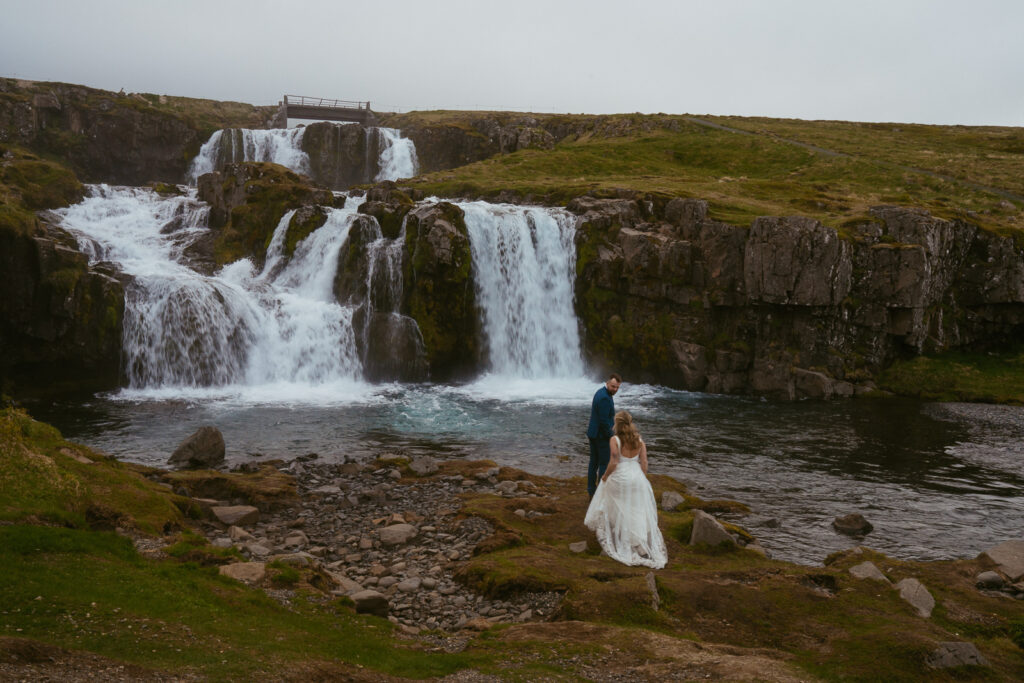 Scenic Iceland wedding portrait at Kirkjufellsfoss with fog and golden light