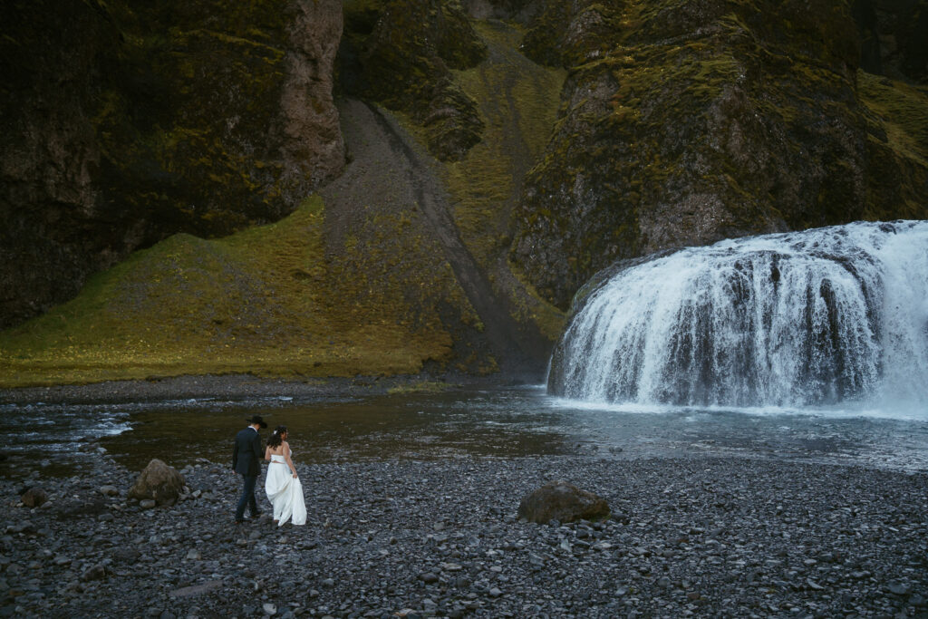 iceland elopement, couple standing in front of a waterfall and walking