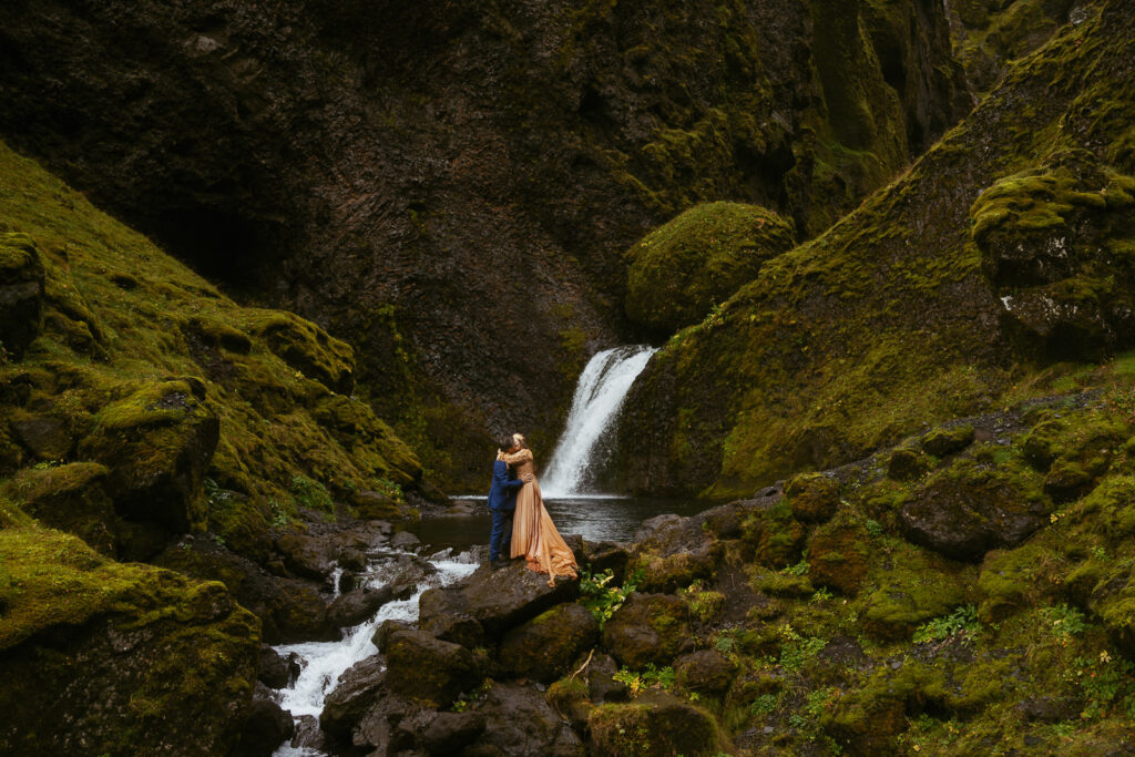 couple eloping in iceland standing in front of a waterfall