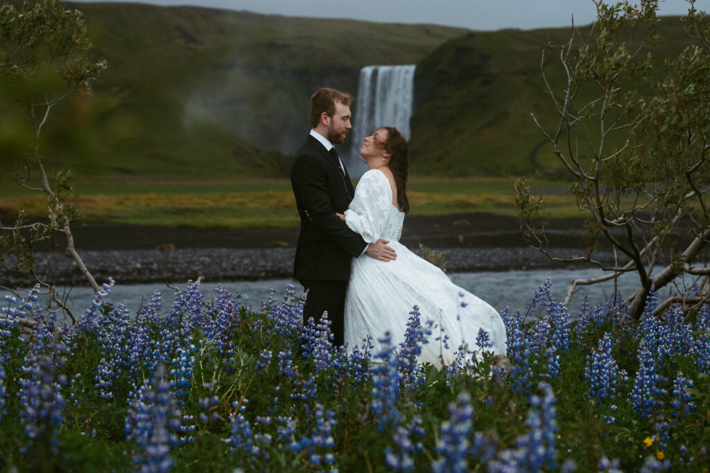 couple in wedding attire running in a lupine field in iceland
