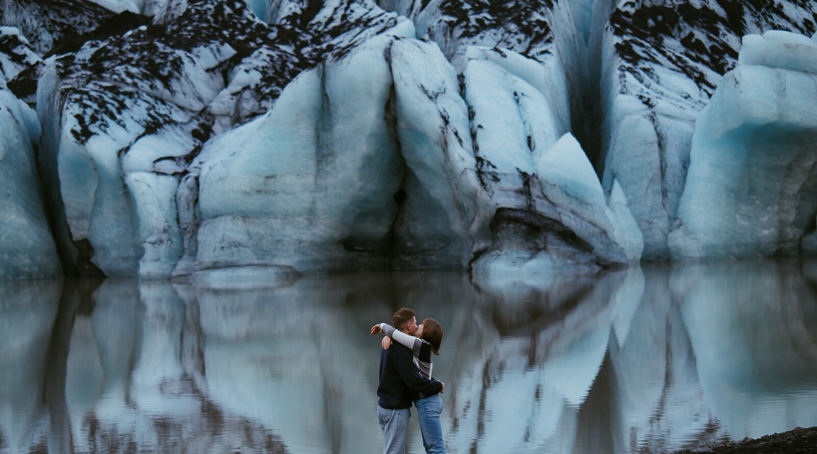 couple standing in front of a glacier in iceland